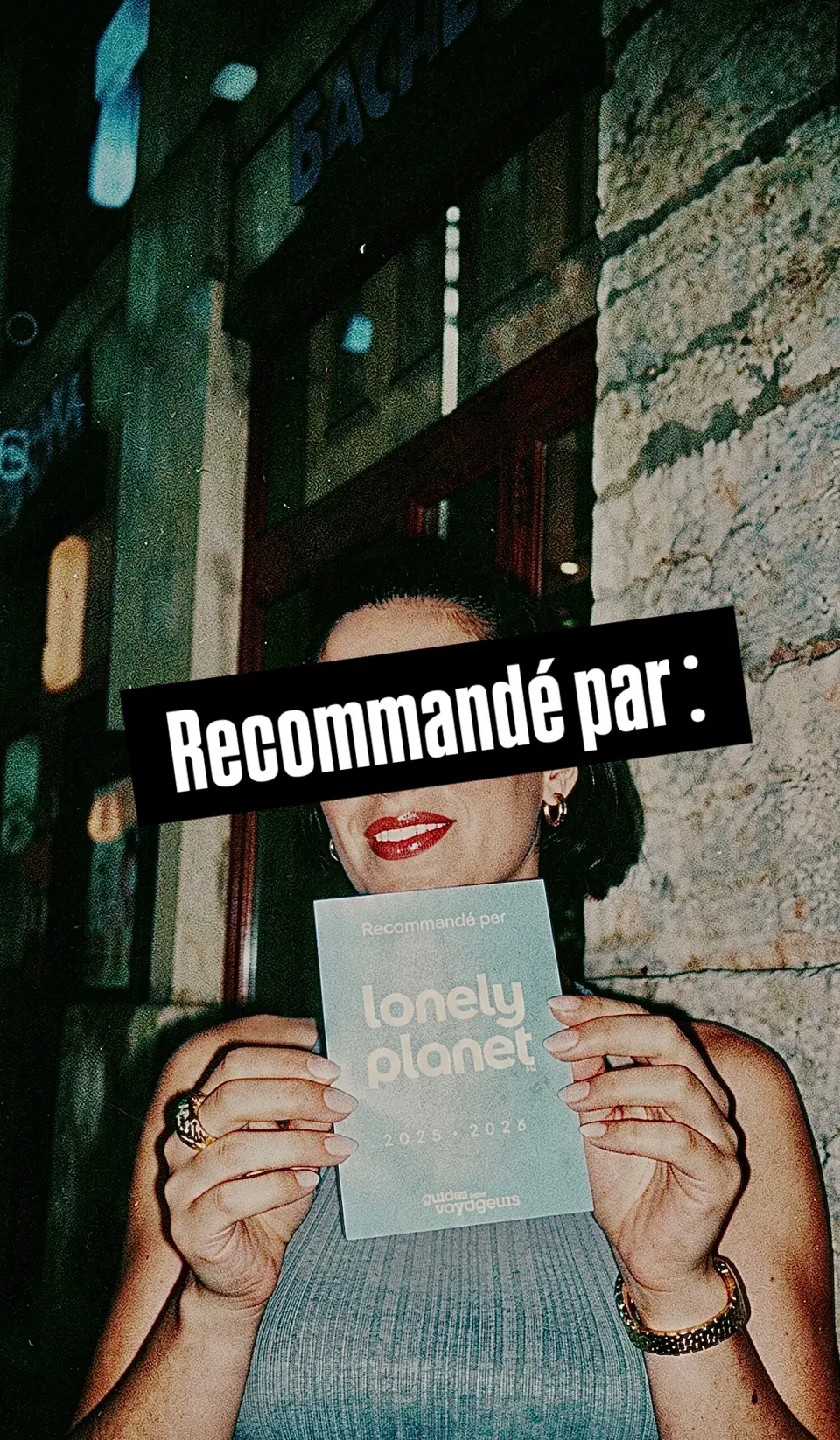 Charlotte tient le sticker « Recommandé par Lonely Planet 2025-2026 » devant le bar