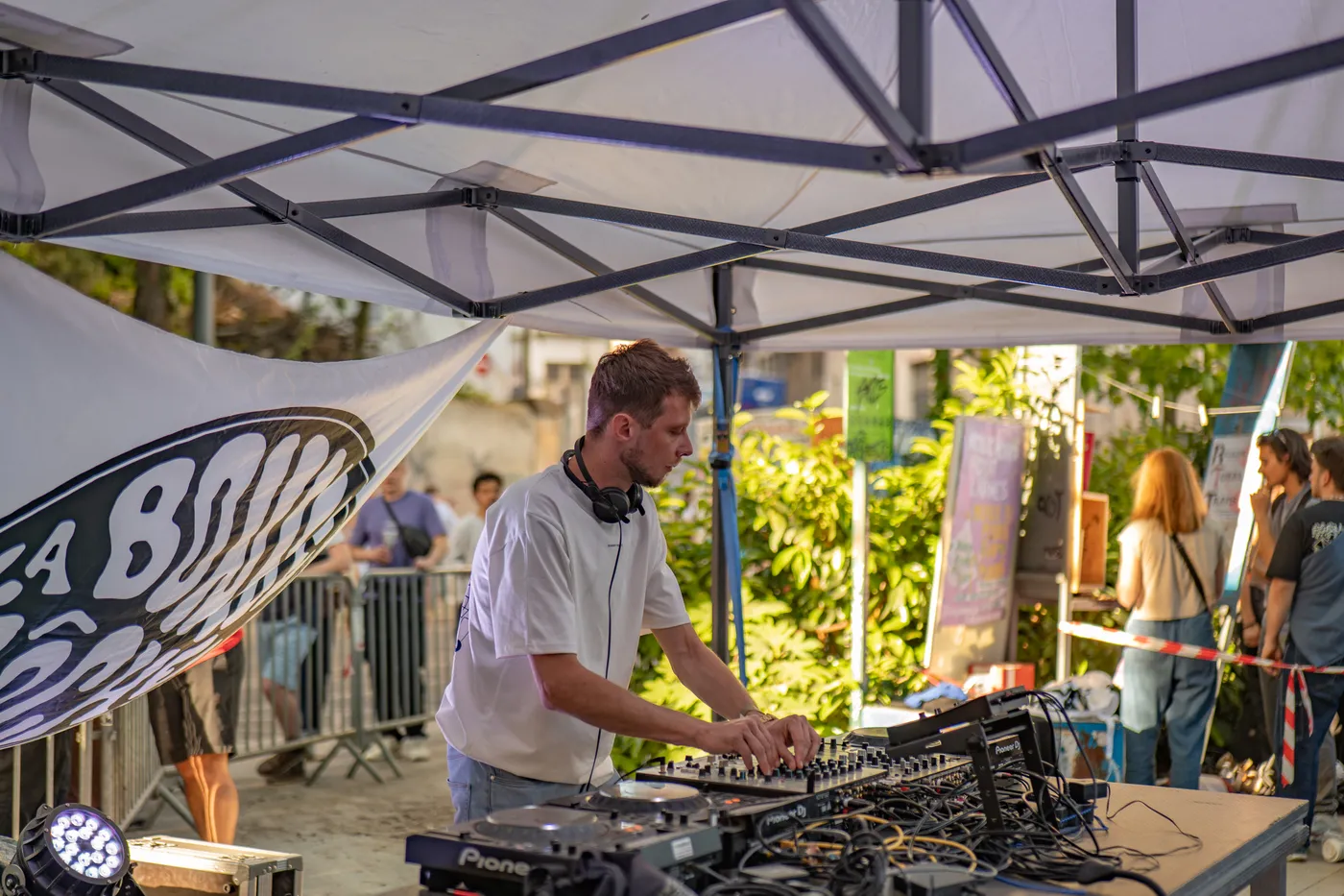 Un DJ aux platines sous le barnum, devant la bâche La Bonne Gâche, pendant un open air à Lyon